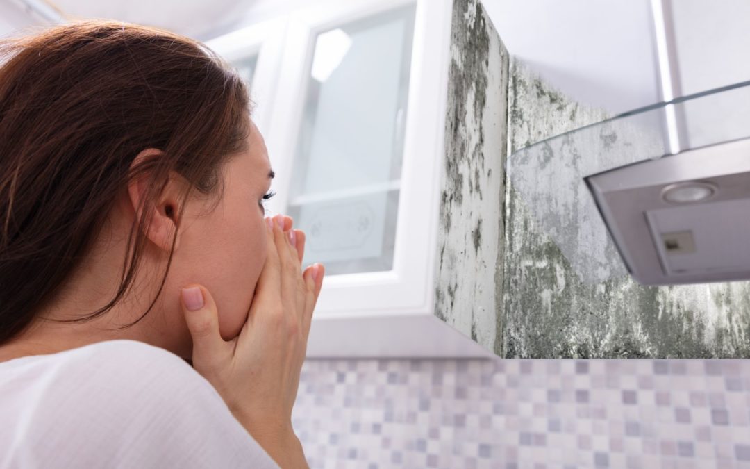 A woman stares at a patch of mold and wonders how to prevent mold and mildew in the bathroom.