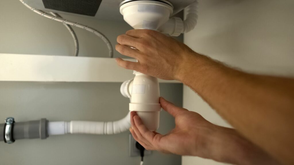 A plumber who knows how to prevent plumbing leaks adjusts a pipe